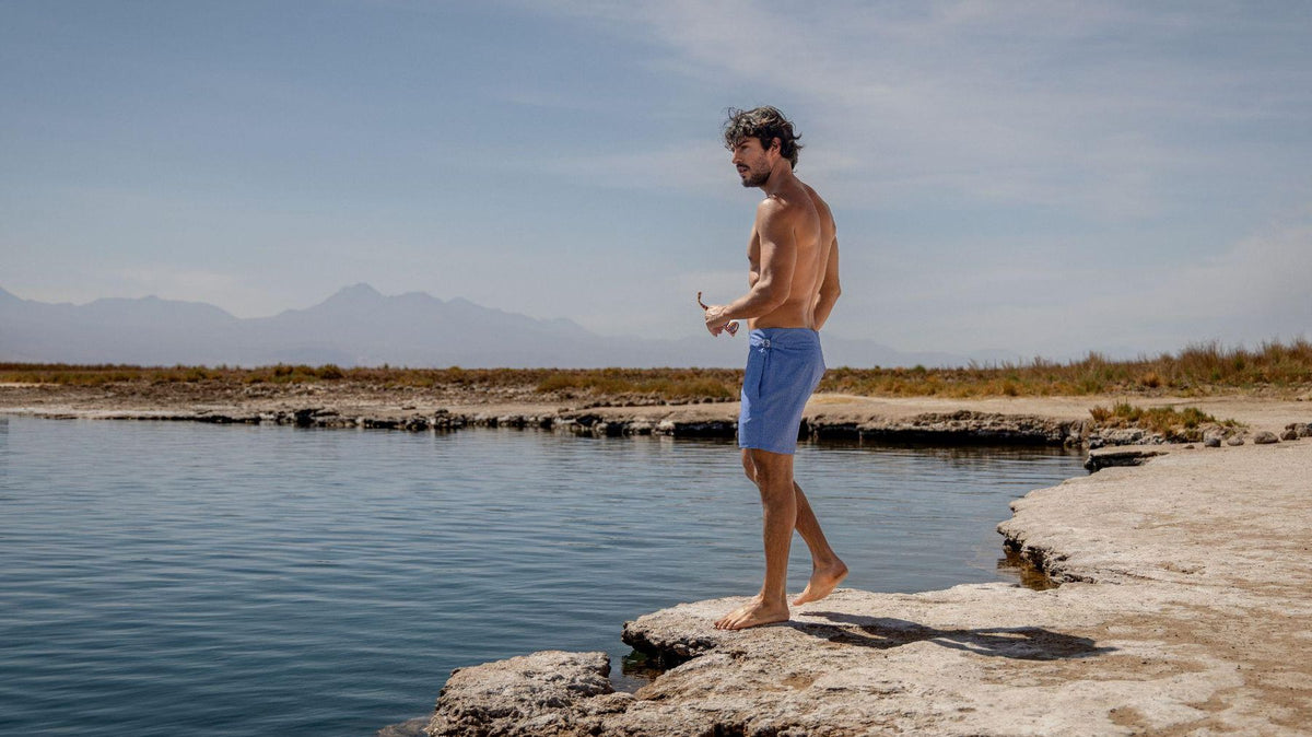 Pré-Summer Sardegna: homem de short de banho azul à beira de uma lagoa
